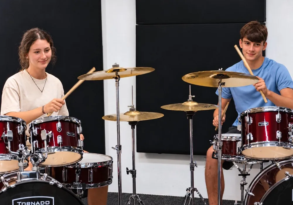 Dos alumnes tocant la bateria junts en una classe de Jambala
